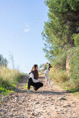 a woman and her dog playing and running in the middle of the forest