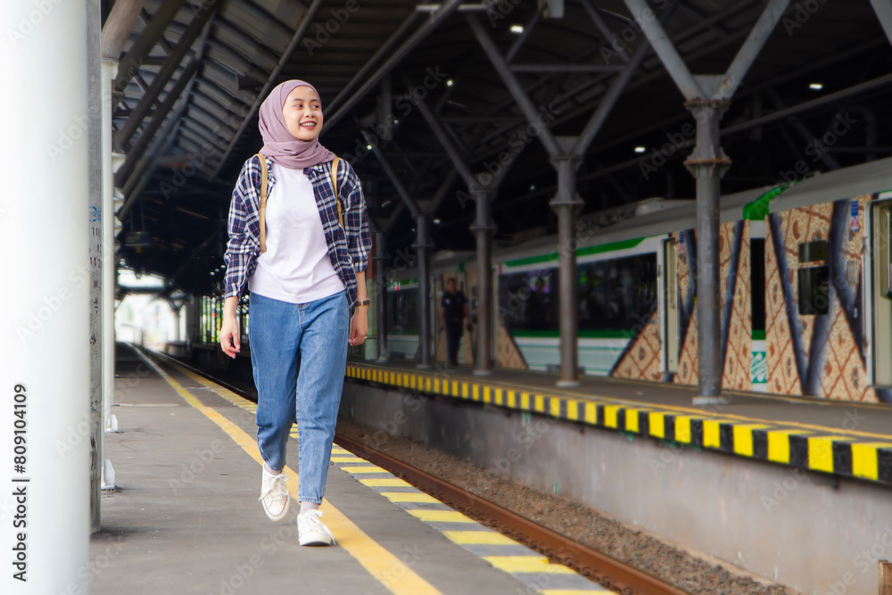 full lenght shoot of asian muslim woman wakling on train station platform. traveling concept