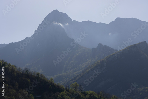 Mountain landscape with peak and cloud on a bright sunny spring day with green vegetation and blue sky in Picos de Europa National Park