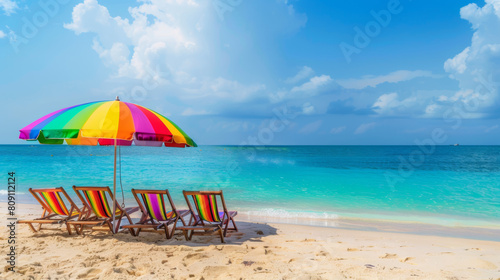 A beach with a colorful umbrella and four beach chairs