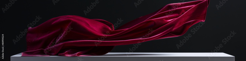 Obraz premium Elegant Red Satin Cloth Flowing Over White Pedestal on Dark Background