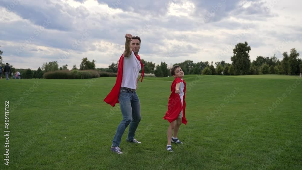 In a vast grassland, father and son in superhero capes run under the cloudfilled sky. Happy family make playful gesture as super heroes who fly to save and protect. 4k high res slow motion In a vast grassland, father and son in superhero capes run under the cloudfilled sky. Happy family make playful gesture as super heroes who fly to save and protect. 4k high res slow motion