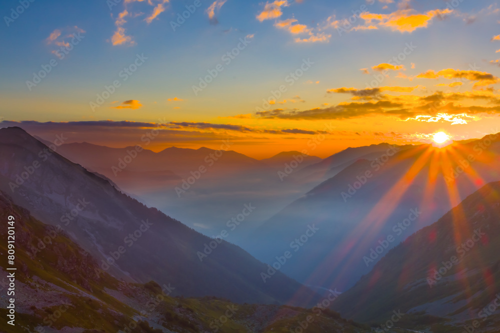 mountain valley silhouette in blue mist at the sunrise
