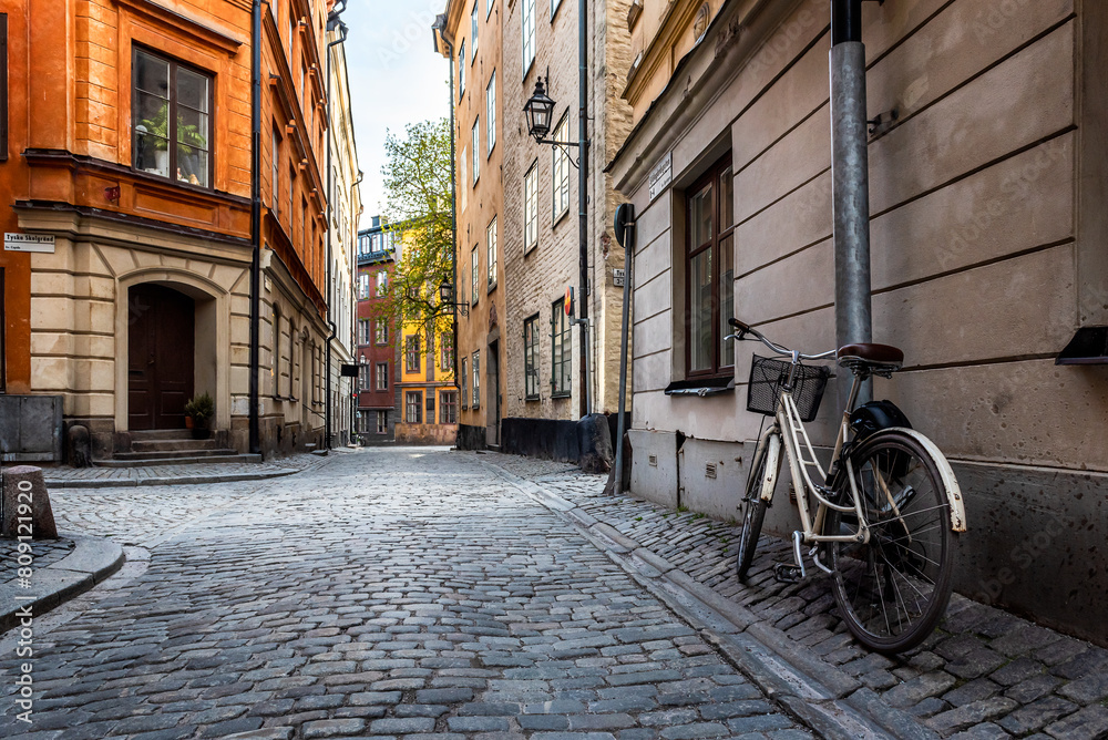 Sweden quaint cobblestone street in picturesque Gamla Stan, Stockholm's oldest neighborhood. Parked bicycles lean against the colorful plaster buildings.