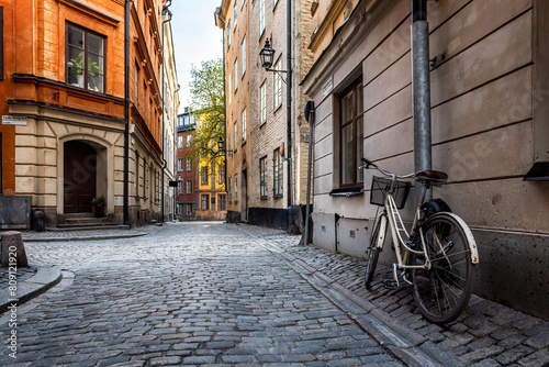 Sweden quaint cobblestone street in picturesque Gamla Stan, Stockholm's oldest neighborhood. Parked bicycles lean against the colorful plaster buildings.
