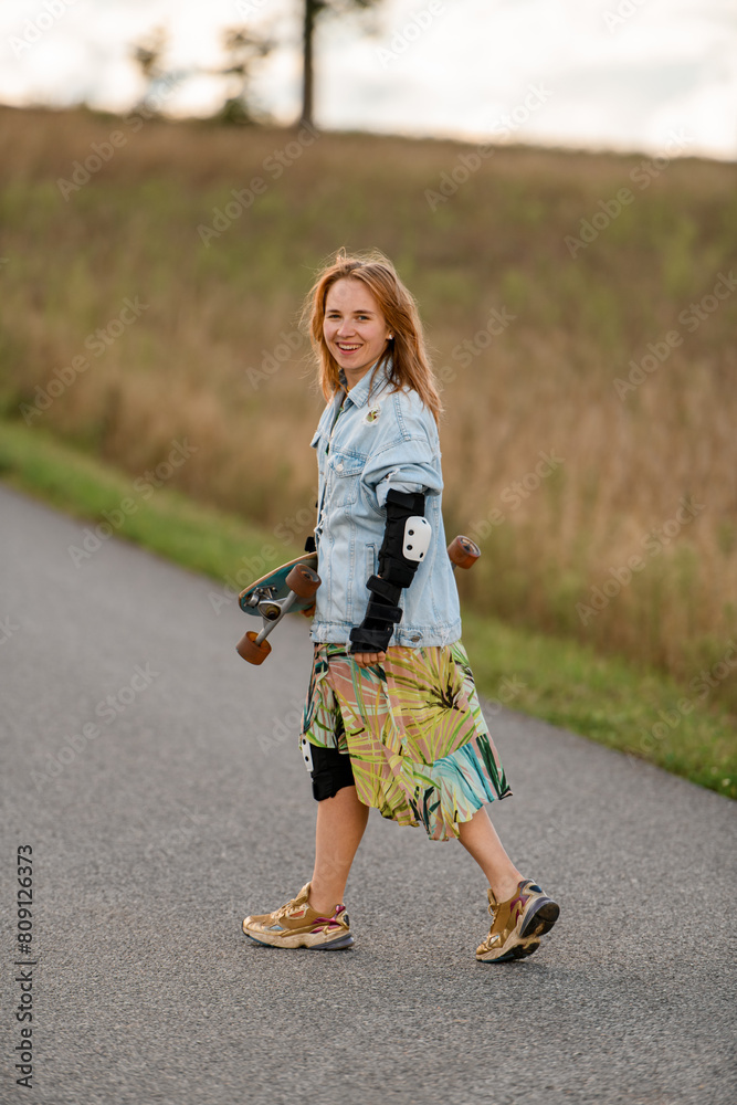 Girl with longboard, smiling, faces the country road's open expanse Girl with longboard, smiling, faces the country road's open expanse