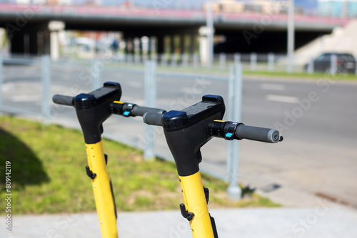 A yellow and black scooter with bicycle handlebar parked on the city road