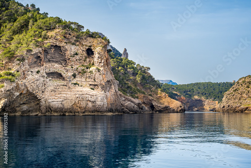 Layered limestone formation at Mallorca coastline, showcasing the Morro de Sant Joan cliff, adorned with Es Penyal Bernat de S'Illeta rock, overlooking Cala Ses Cambres cove and Torre Picada tower. photo