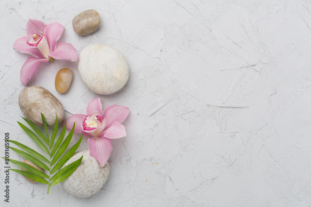 Composition with orchids and massage stones on concrete background, top view Composition with orchids and massage stones on concrete background, top view