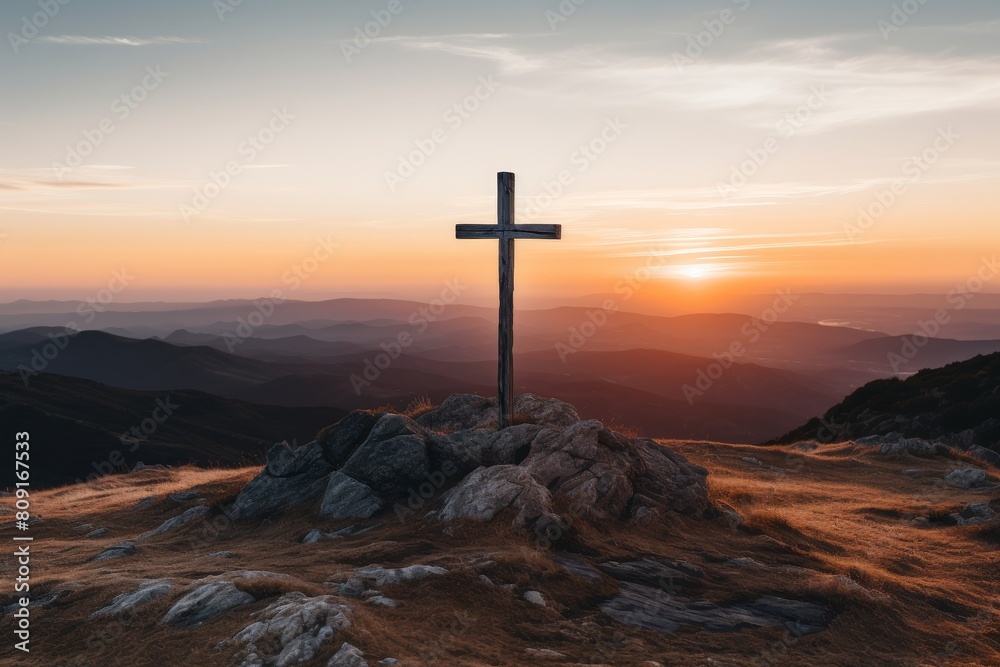 Wooden cross on rocky mountain at sunset