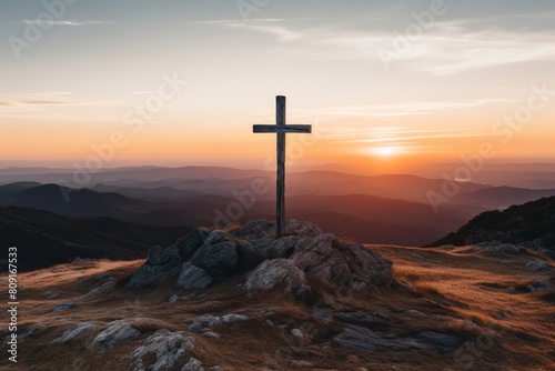 Wooden cross on rocky mountain at sunset