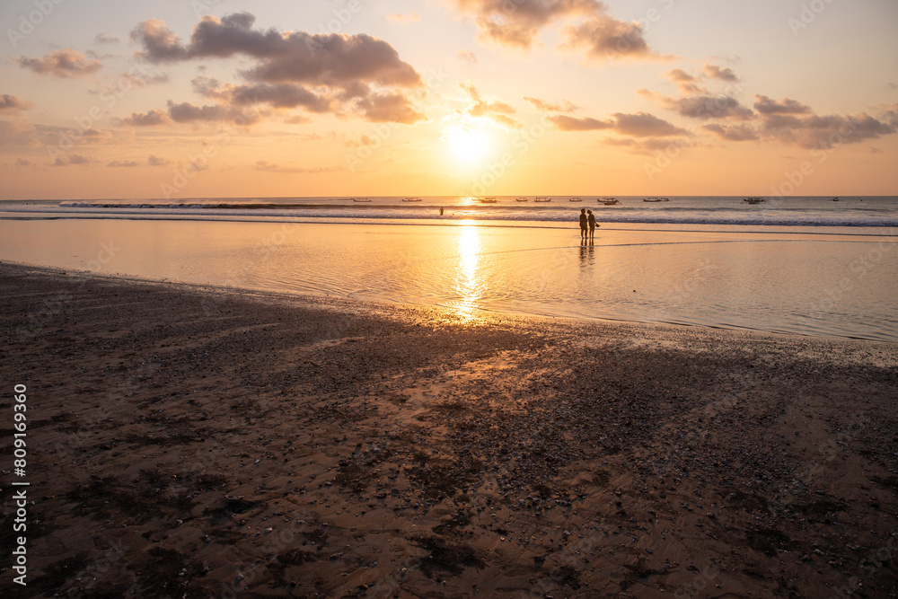 Fantastic sunset on the dream beach of Kuta, small waves setting over the sea and the reflection of the sky in the shallow water. News Bali in Indonesia