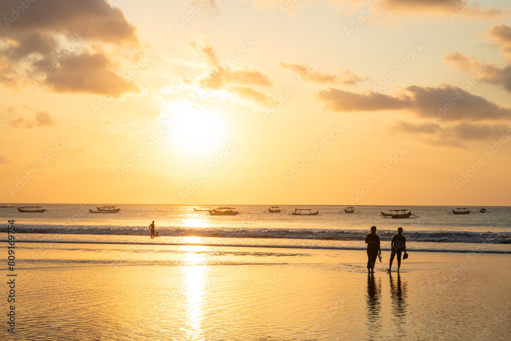 Fantastic sunset on the dream beach of Kuta, small waves setting over the sea and the reflection of the sky in the shallow water. News Bali in Indonesia