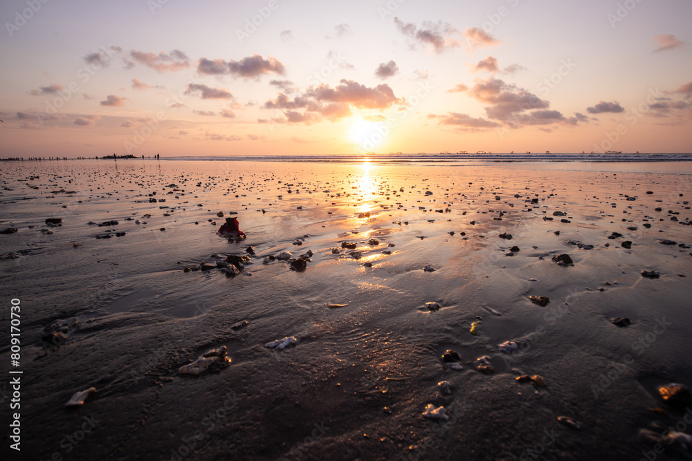 Fantastic sunset on the dream beach of Kuta, small waves setting over the sea and the reflection of the sky in the shallow water. News Bali in Indonesia Fantastic sunset on the dream beach of Kuta, small waves setting over the sea and the reflection of the sky in the shallow water. News Bali in Indonesia