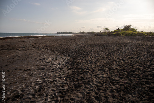 Black sand beach in Bali, of course with temples, boats (jukung) and waves at sunrise. The tropical climate in Indonesia in the morning