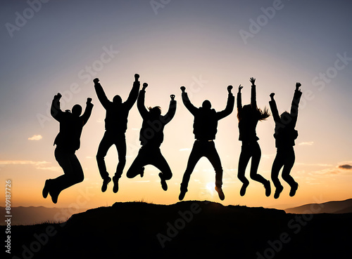 Silhouette of group of people jumping in the air in back of bright sunrise in mountain