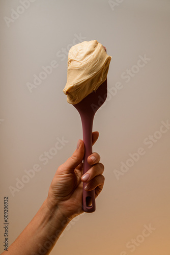 Pastry chef hand holding natural light beige whipped cream