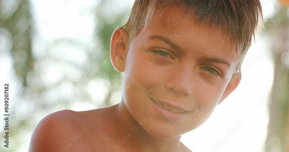 Child looking to camera smiling portrait of young boy outside with lens-flare sunlight Child looking to camera smiling portrait of young boy outside with lens-flare sunlight