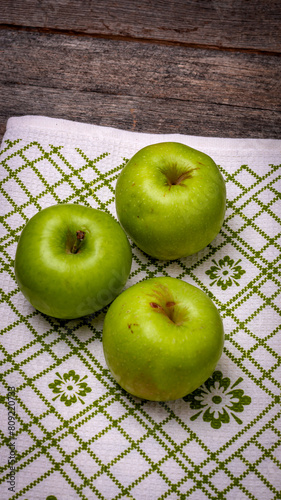  Ripe green apples on a rustic napkin on wooden table.