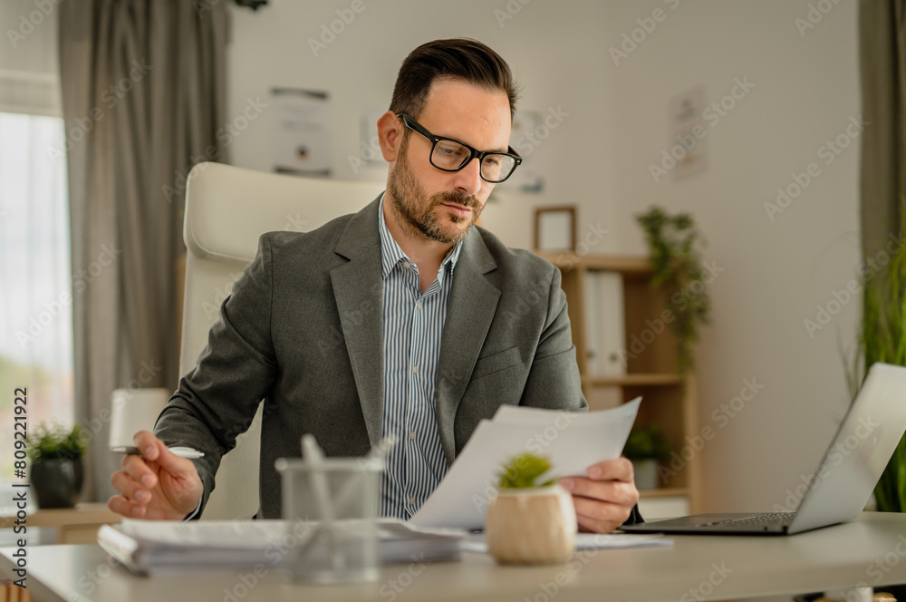 One men working in the office using technology and looking at paper One men working in the office using technology and looking at paper