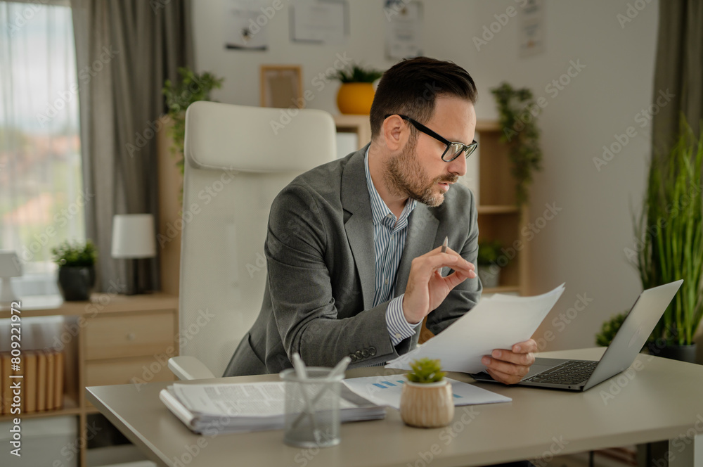 One men working in the office using technology and looking at paper One men working in the office using technology and looking at paper