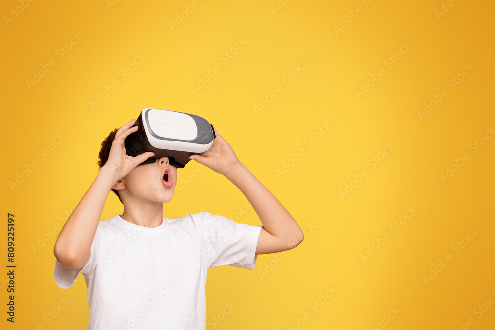 A young boy wearing a white t-shirt holding a black and white virtual globe in his hands. A young boy wearing a white t-shirt holding a black and white virtual globe in his hands.