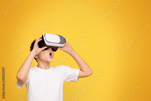 A young boy wearing a white t-shirt holding a black and white virtual globe in his hands.