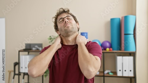 Hispanic man stretching neck in a rehab clinic, depicting a therapeutic exercise routine indoors. photo