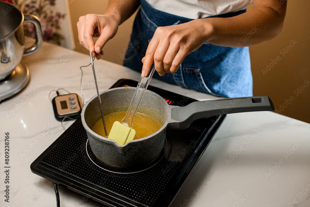 Hot stove and chef's in hands takes butter for the cream Hot stove and chef's in hands takes butter for the cream