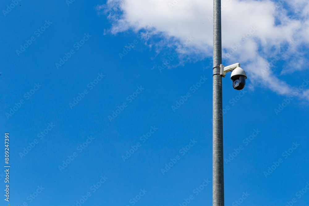 Security camera and urban video in front of blue sky. Outdoor cctv video surveillance cameras. Safety system area control outdoor with copy space. Security camera on a light pole on the street. Security camera and urban video in front of blue sky. Outdoor cctv video surveillance cameras. Safety system area control outdoor with copy space. Security camera on a light pole on the street.