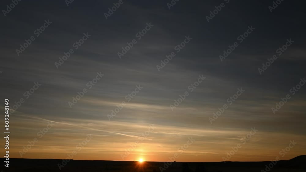 Time lapse of a colorful sunrise with the sun slowly rising above the horizon. The midground is a flat treeless prairie with small hills.
Time lapse of a colorful sunrise with the sun slowly rising above the horizon. The midground is a flat treeless prairie with small hills.