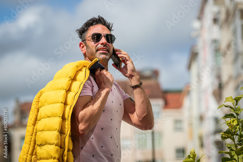 man with sunglasses on the street outdoors with mobile phone