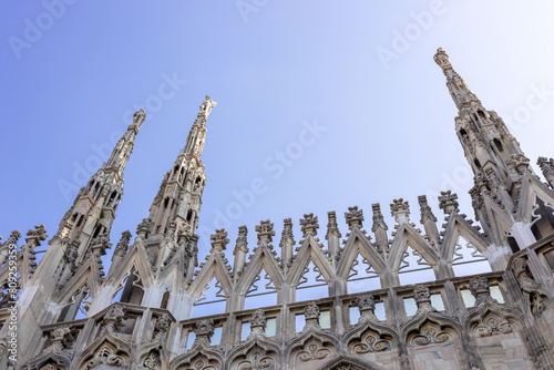 Roof of Milan Cathedral Duomo di Milano with Gothic spires and white marble statues. Top tourist attraction on piazza in Milan, Lombardia, Italy. Gothic architectural fragment photo