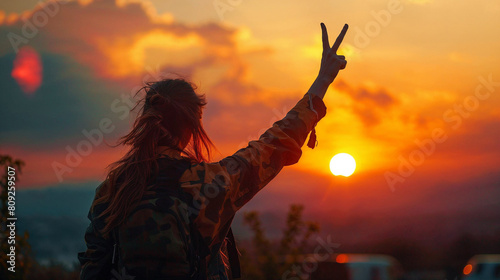 Woman Making Peace Sign Against Vibrant Sunset Sky