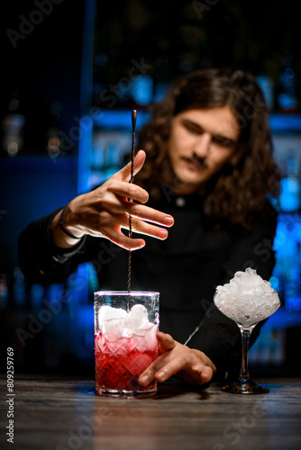 Bartender stirs the wine cocktail with ice using a long bar spoon