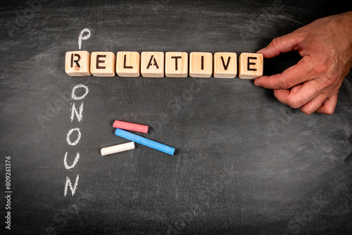 Relative pronoun. Wooden block crossword puzzle and pieces of chalk on a chalkboard background photo