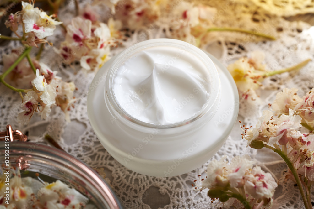 Horse chestnut cream in a glass jar with fresh Aesculus hippocastanum flowers collected in spring