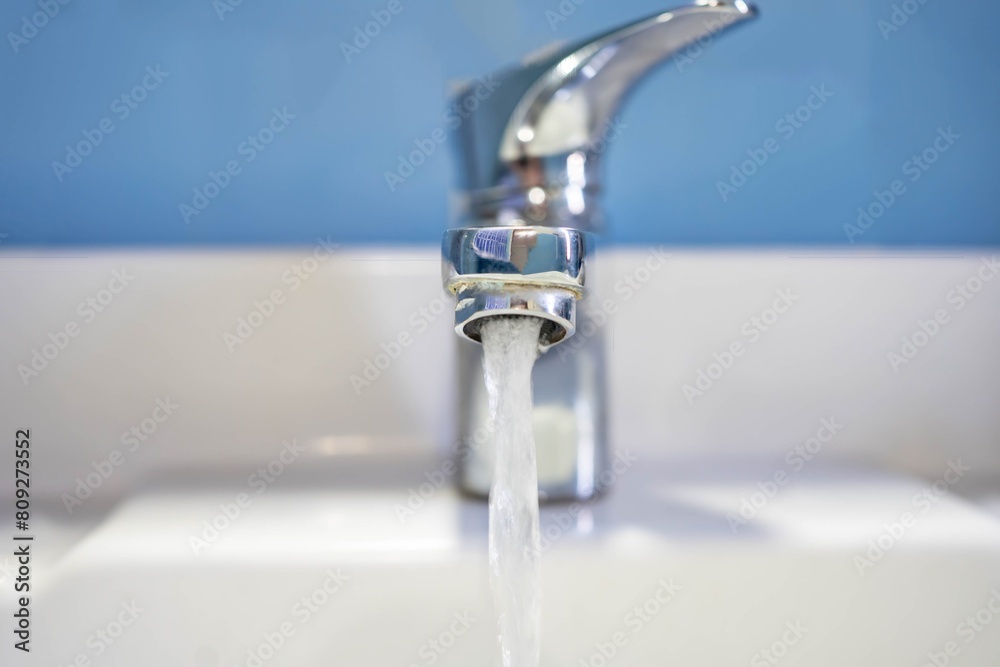 Front view of water flow from the sink. Old sink with clean water on blue background. Front view of water flow from the sink. Old sink with clean water on blue background.