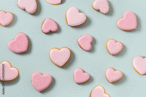 Seamless pattern of heart shaped cookies with pink glaze on blue background. Valentines day wallpaper or greeting card.