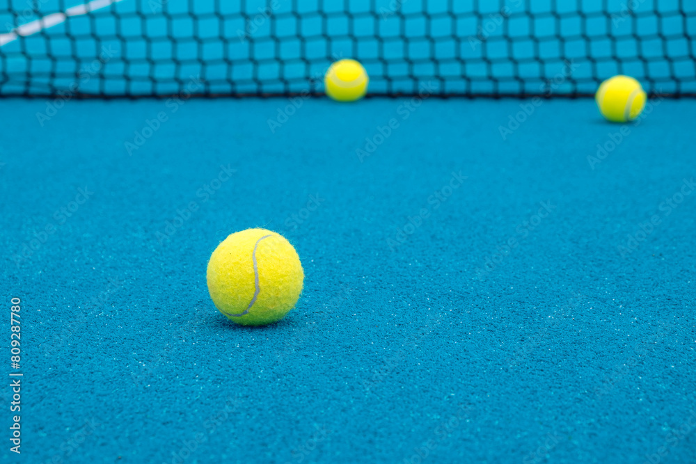 Selective focus. Paddle tennis balls on an open blue paddle tennis court. Racket sports concept