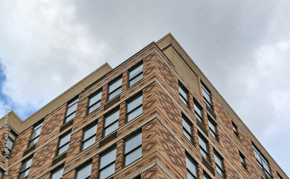 tall apartment building detail with colorful bricks, windows reflecting cloudy sky (housing real estate flats new jersey waterfront) tall apartment building detail with colorful bricks, windows reflecting cloudy sky (housing real estate flats new jersey waterfront)