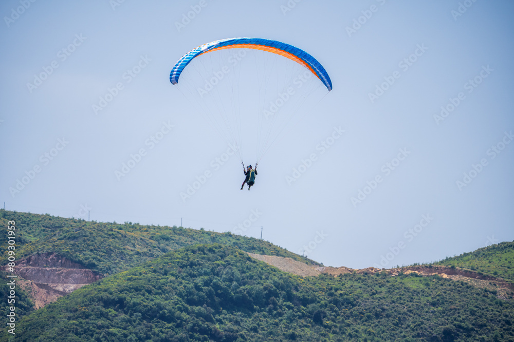 Paraglider flying over mountains in summer day Paraglider flying over mountains in summer day