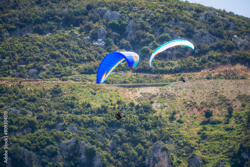 Paraglider flying over mountains in summer day