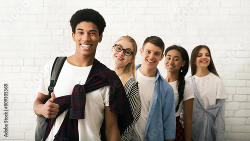 Φωτογραφία Five cheerful teenagers, three girls and two boys, are seen lined up against a white brick wall background