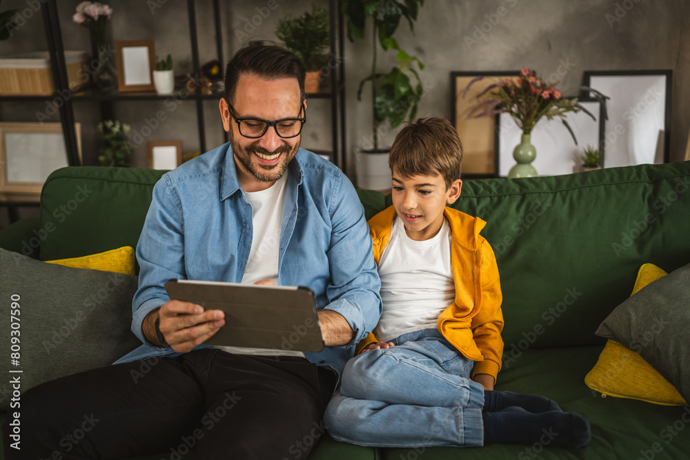 Father with eyeglasses and son use tablet for homework browse internet Father with eyeglasses and son use tablet for homework browse internet
