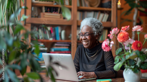 Happy senior black woman working remotely at laptop. Smiling mature african american on video call team meeting. Grandmother staying connected digitally with family