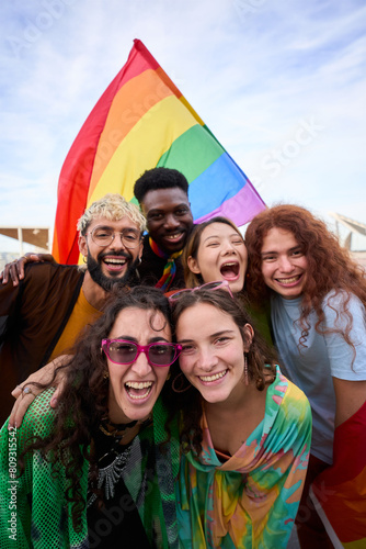 Diverse group of happy young people taking funny vertical selfie for social media celebrating gay pride festival day. Lgbt community concept cheerful friends outdoors. Generation z enjoy party.