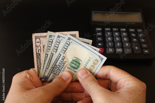 man counting US dollars money with his hand. US banknotes. The paper currency of usa .Calculator in the background.