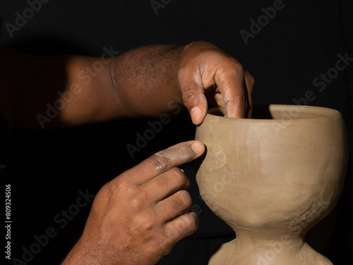 Close-up portrait of artisan's hand shaping ceramic pot. Clay art photo