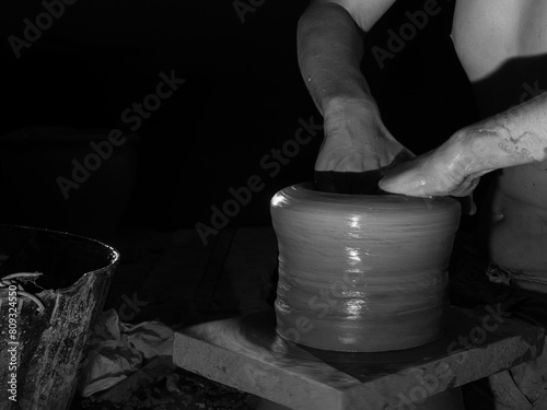 Close-up black and white portrait of artisan hands shaping ceramic pot. Clay art photo